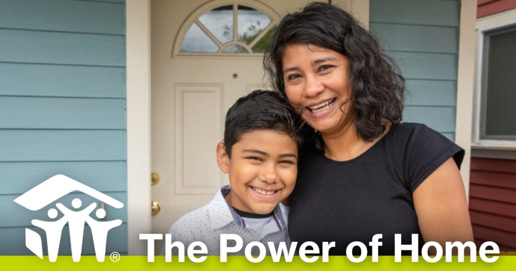 Habitat homeowner and her son smile in front of their new home