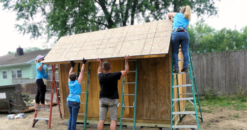 Volunteers raise the roof of a shed during Rock the Block 2023.