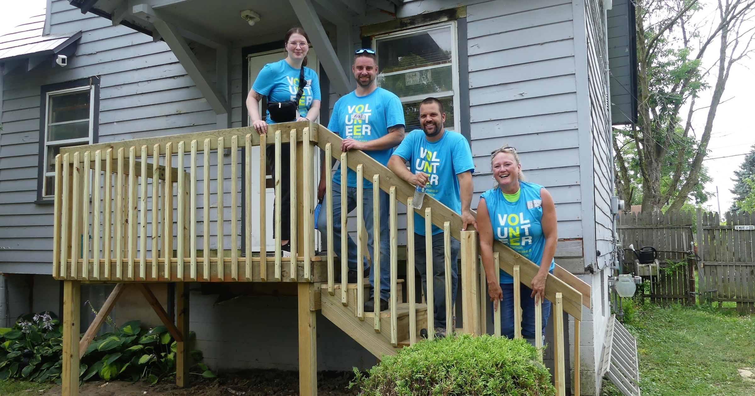 Volunteers stand on Peggy new front steps after completing them during Rock the Block 2023.