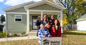 Brittni's family home: Brittni and her four kids stand in front of their completed Habitat home with a sold sign and the keys raised in the air.