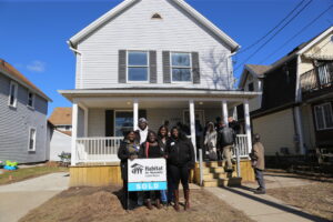 Martha and her family stand in front of her new home, with a Habitat "SOLD" sign in front.